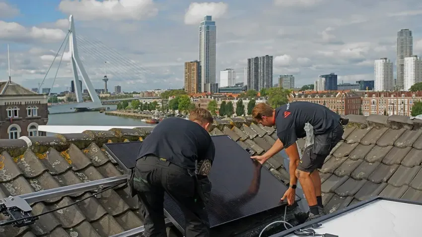 Espacio representativo del hotel: Trabajadores instalan un panel solar en un tejado de tejas con vistas a la ciudad.