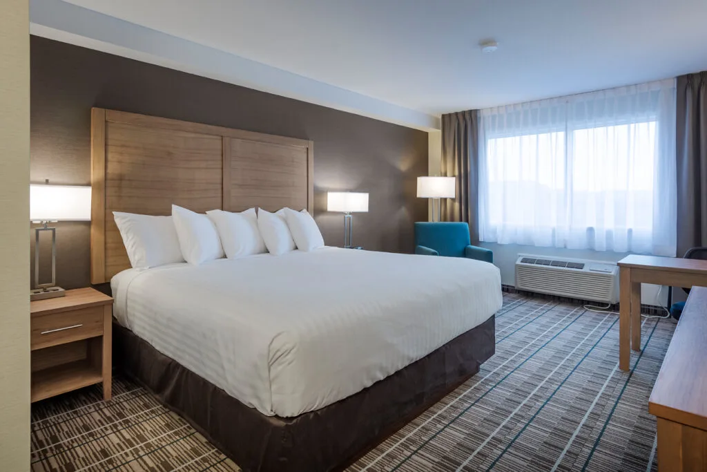 Espacio representativo del hotel: Un dormitorio de hotel con una cama grande y una ventana luminosa.