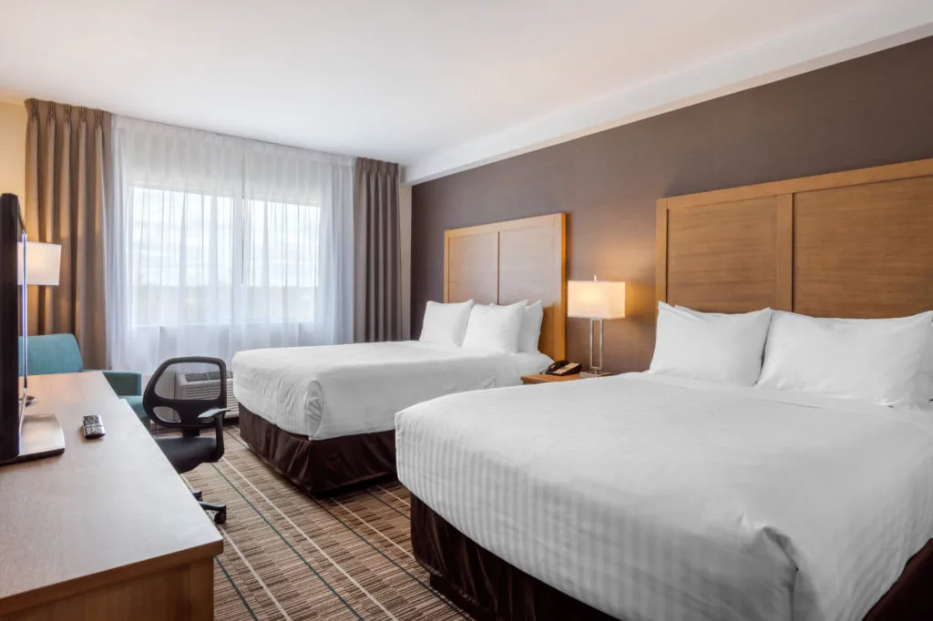 Espacio representativo del hotel: Un dormitorio de hotel con dos camas junto a una gran ventana con cortinas.