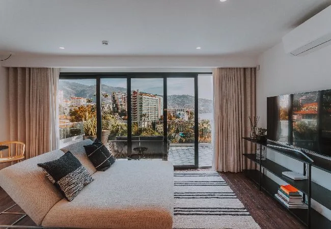 A living room with a sofa facing large windows and a city view.
