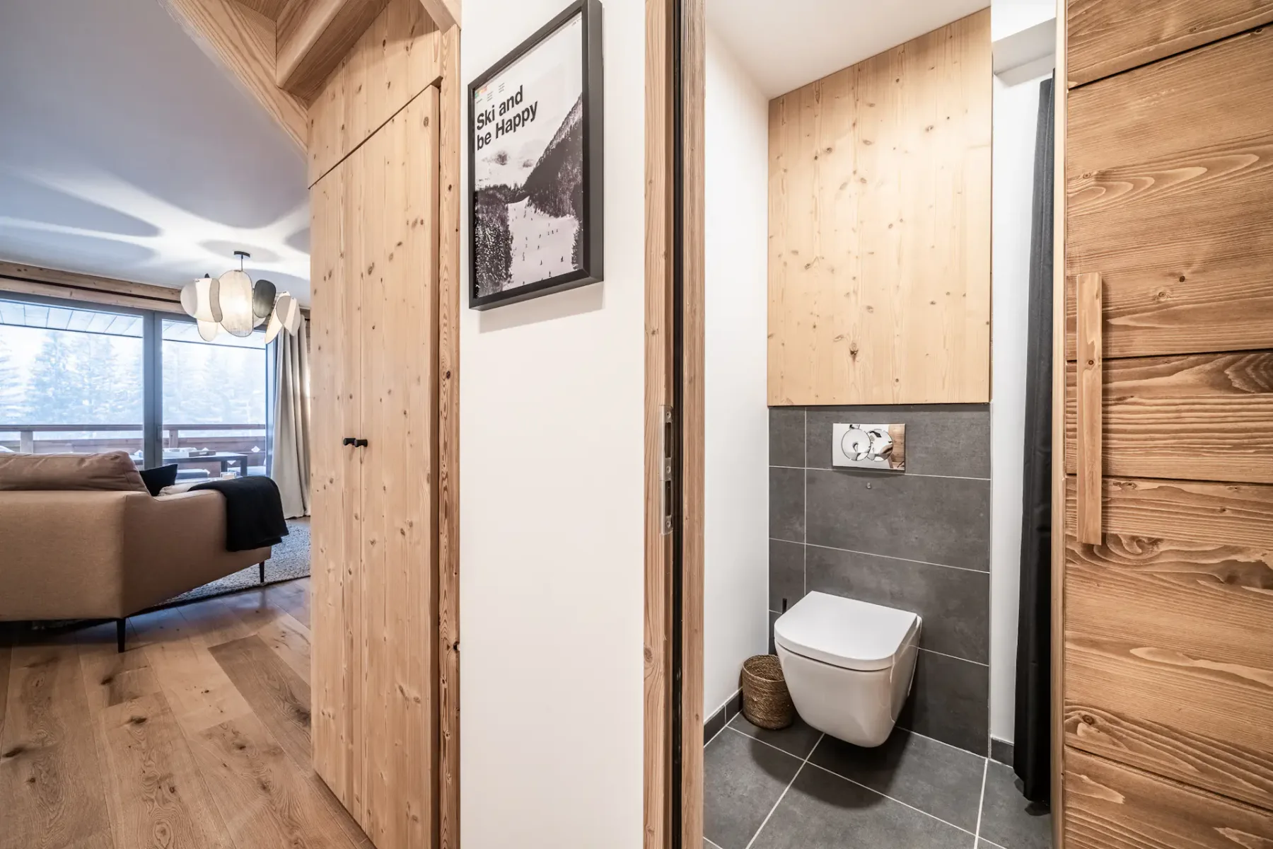 A compact bathroom with a wall-mounted toilet and dark tiled walls.