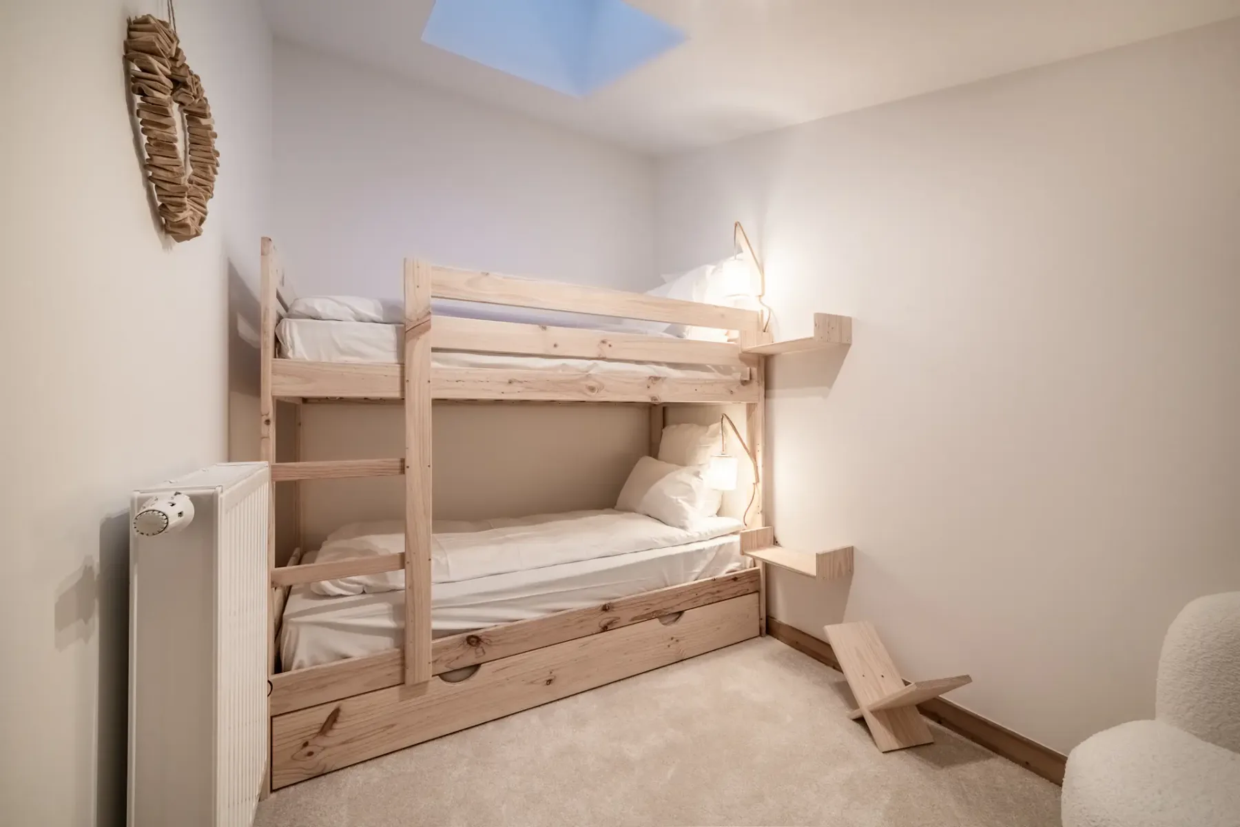 A bedroom with a wooden bunk bed and a small skylight.