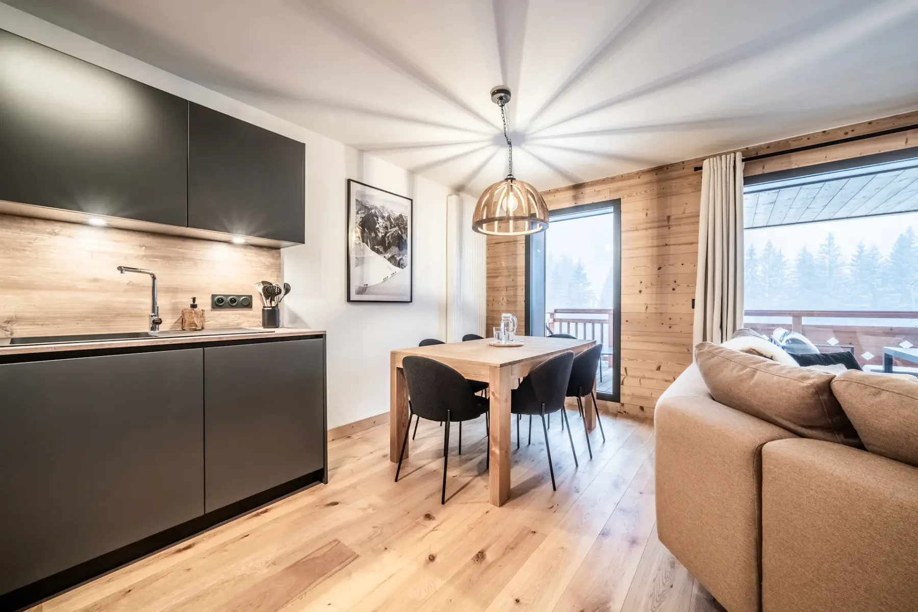An open-plan living and dining area with a kitchenette and large windows.