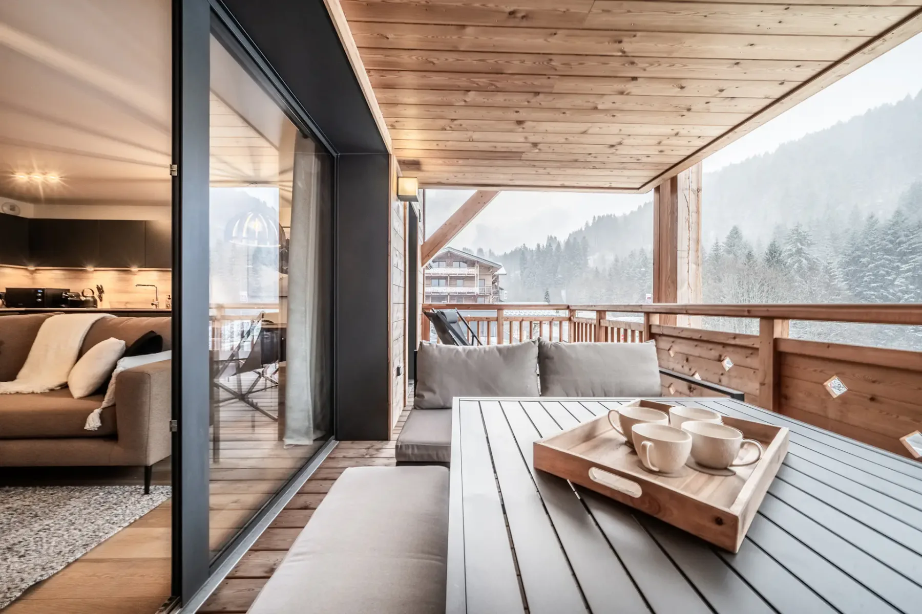 A covered wooden balcony with a low table and views of the surrounding hills.
