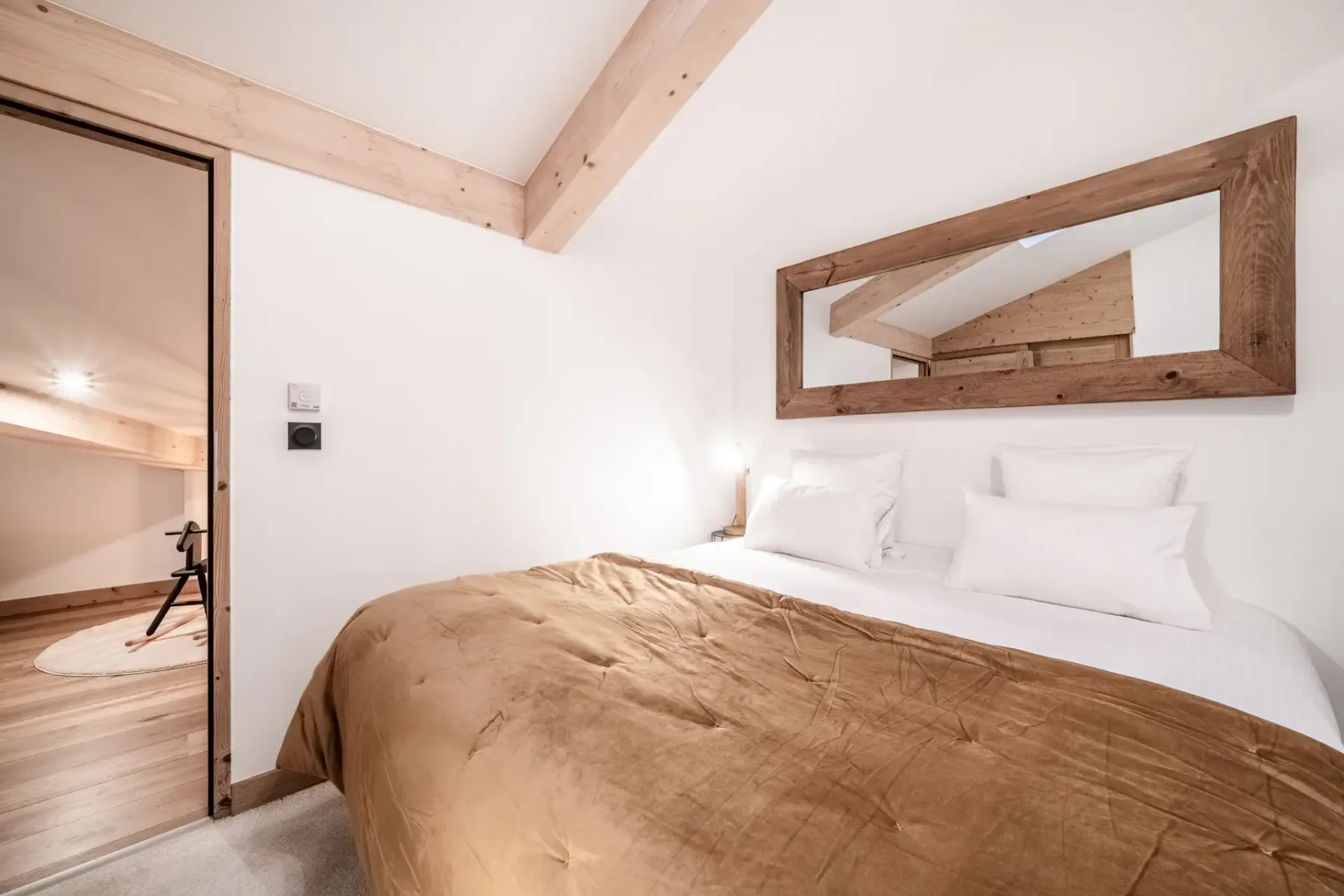 A bedroom with a bed dressed in white linens and a brown cover.