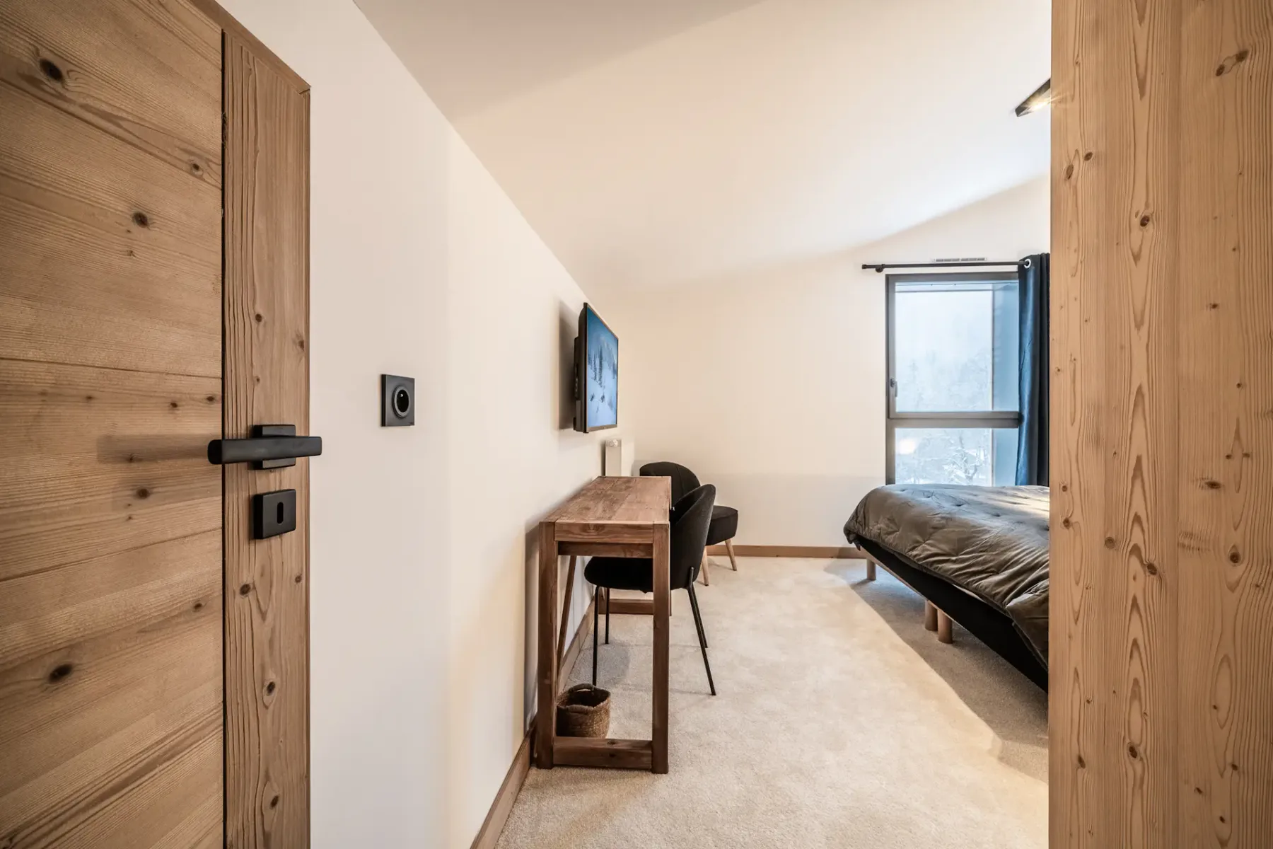 A bedroom with a bed, desk, and window.