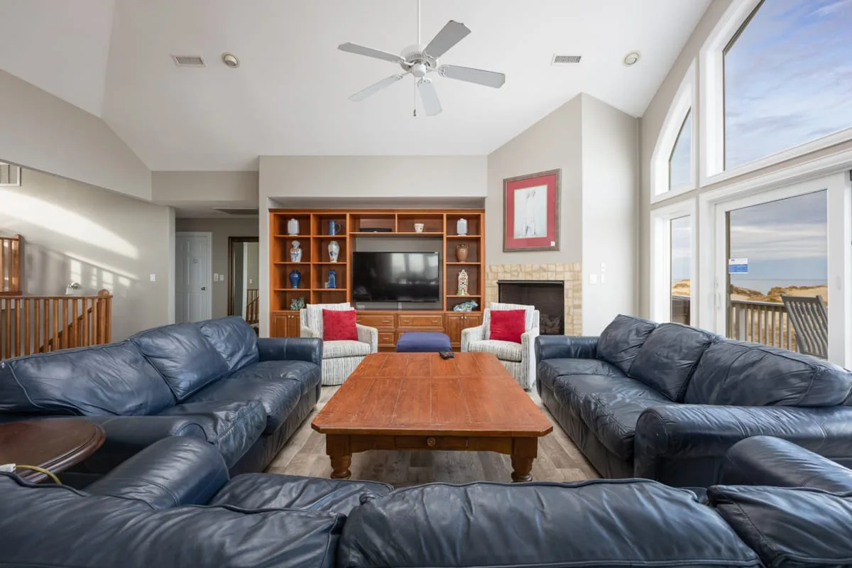 A living room with dark seating arranged around a wooden coffee table and television.