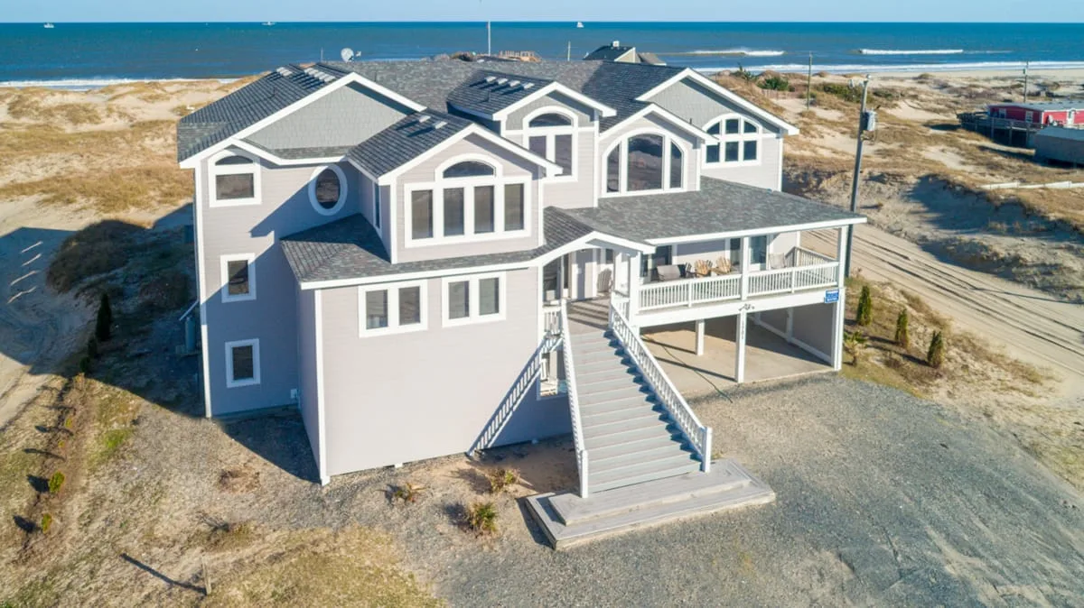 Una amplia casa costera con porche elevado y escalera exterior.