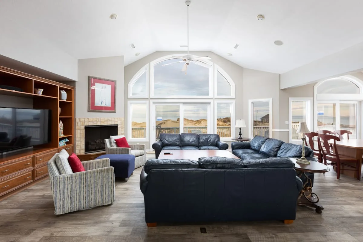 A bright living room with dark seating and large arched windows.