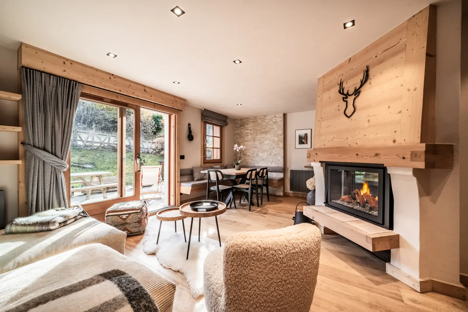 A living room with a fireplace, seating, and a dining area by the windows.