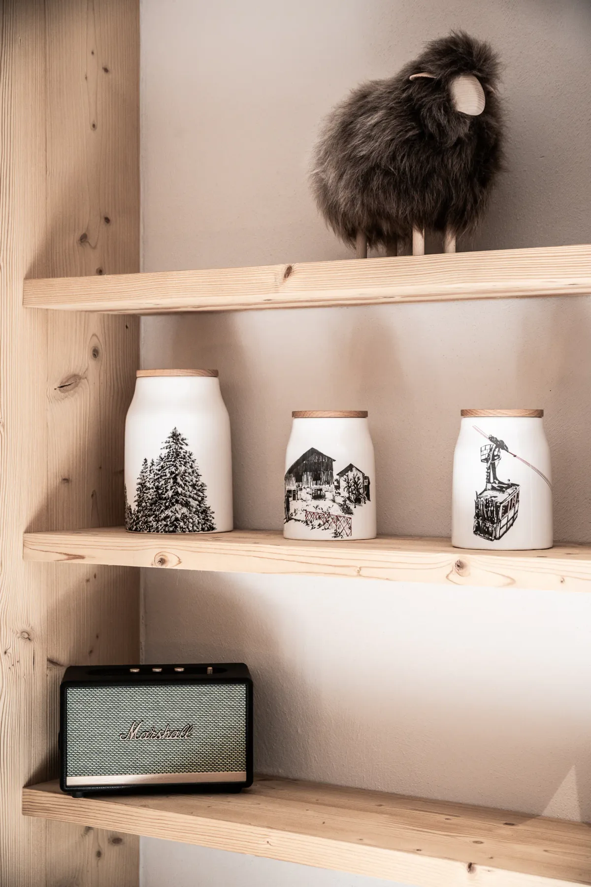 Wooden shelves display ceramic jars, a dark decorative figure, and a speaker.