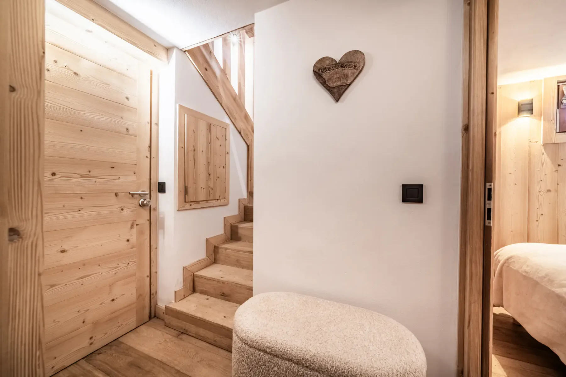 A wood-paneled hallway with stairs and a doorway to a bedroom.