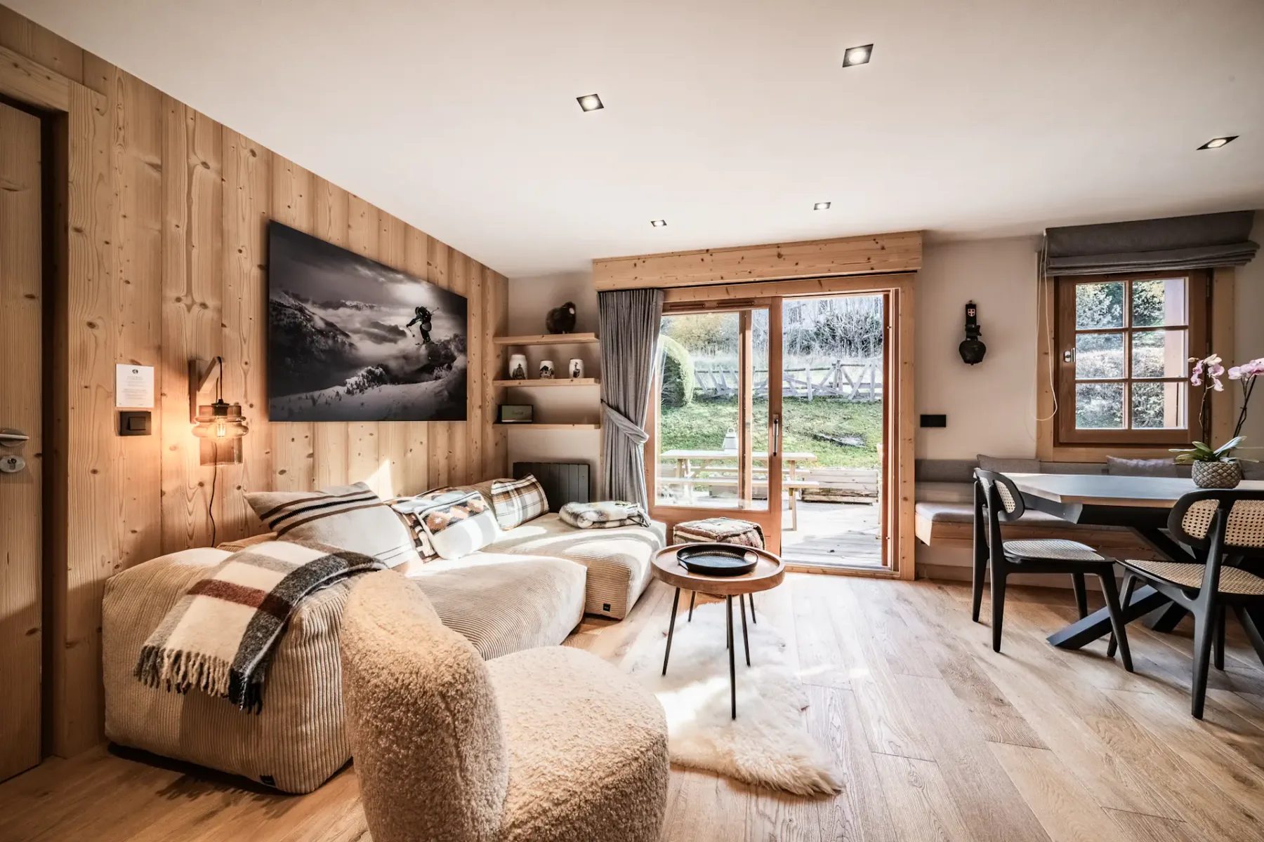 A wood-paneled living room with seating, a coffee table, and doors opening to a garden.