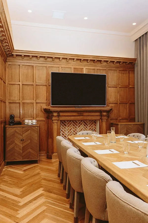 Representative hotel space: A wood-paneled meeting room has a long table and a wall-mounted screen.