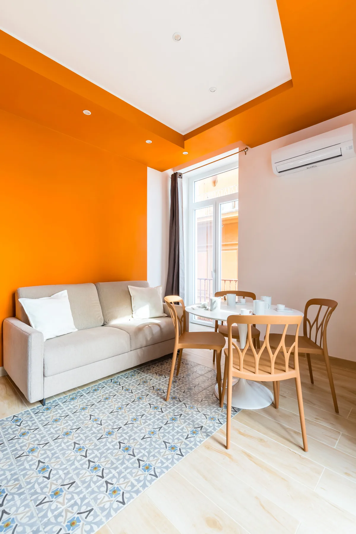 Una luminosa sala de estar con sofá, mesa de comedor y paredes naranjas.