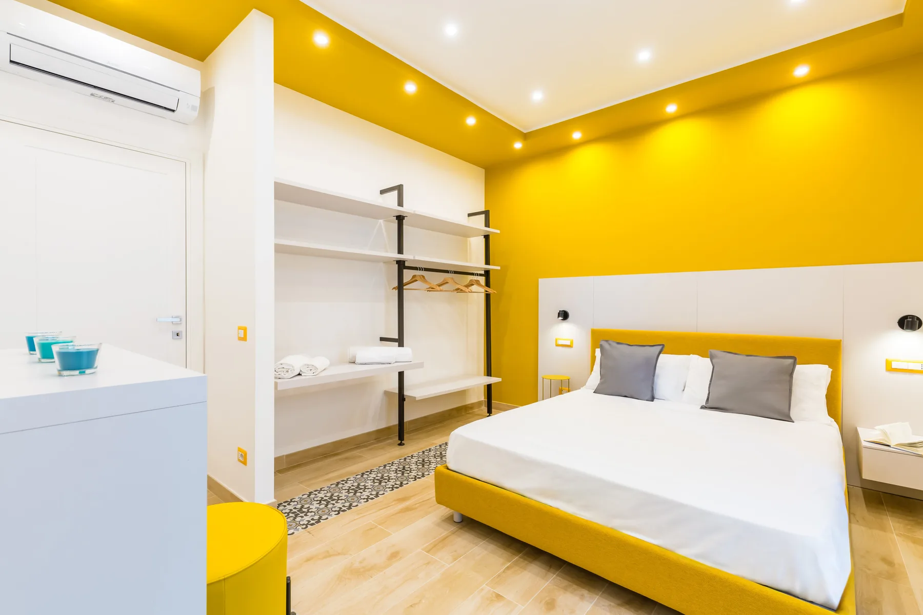 Un dormitorio luminoso con una cama, estantes abiertos y paredes amarillas.