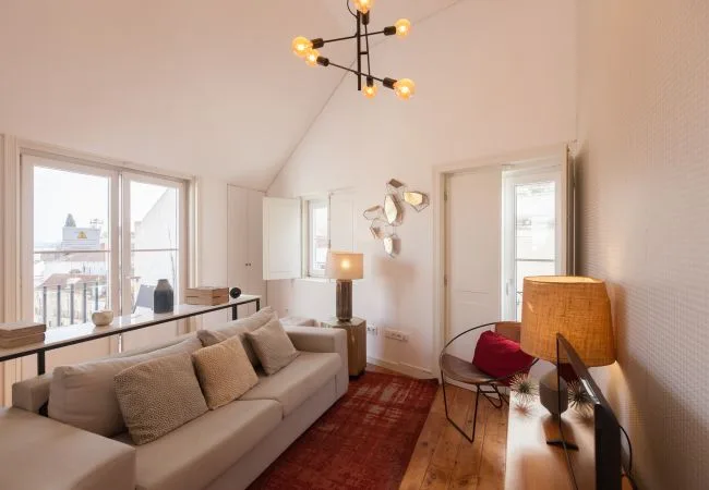A bright living room with seating, a rug, and large windows.