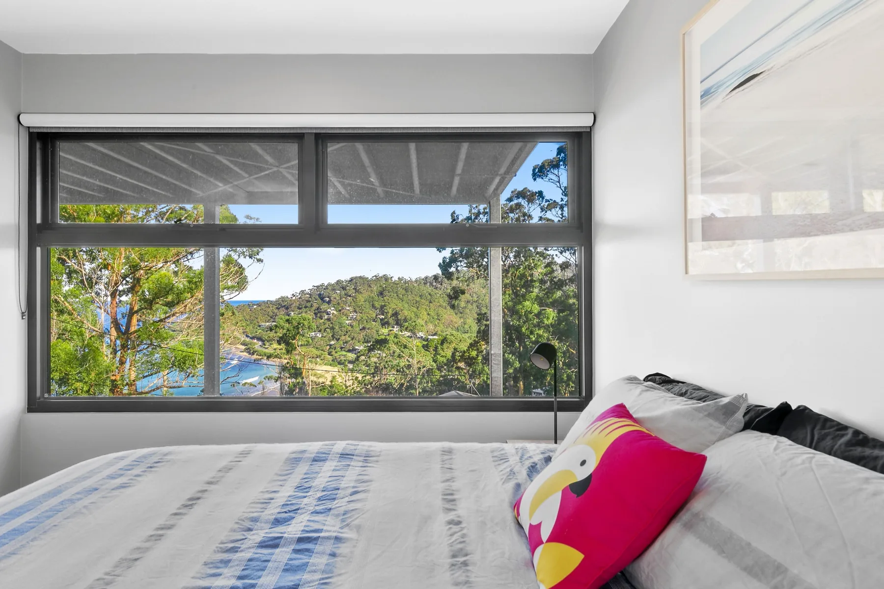 Un dormitorio con una cama junto a una amplia ventana con vistas a colinas verdes.