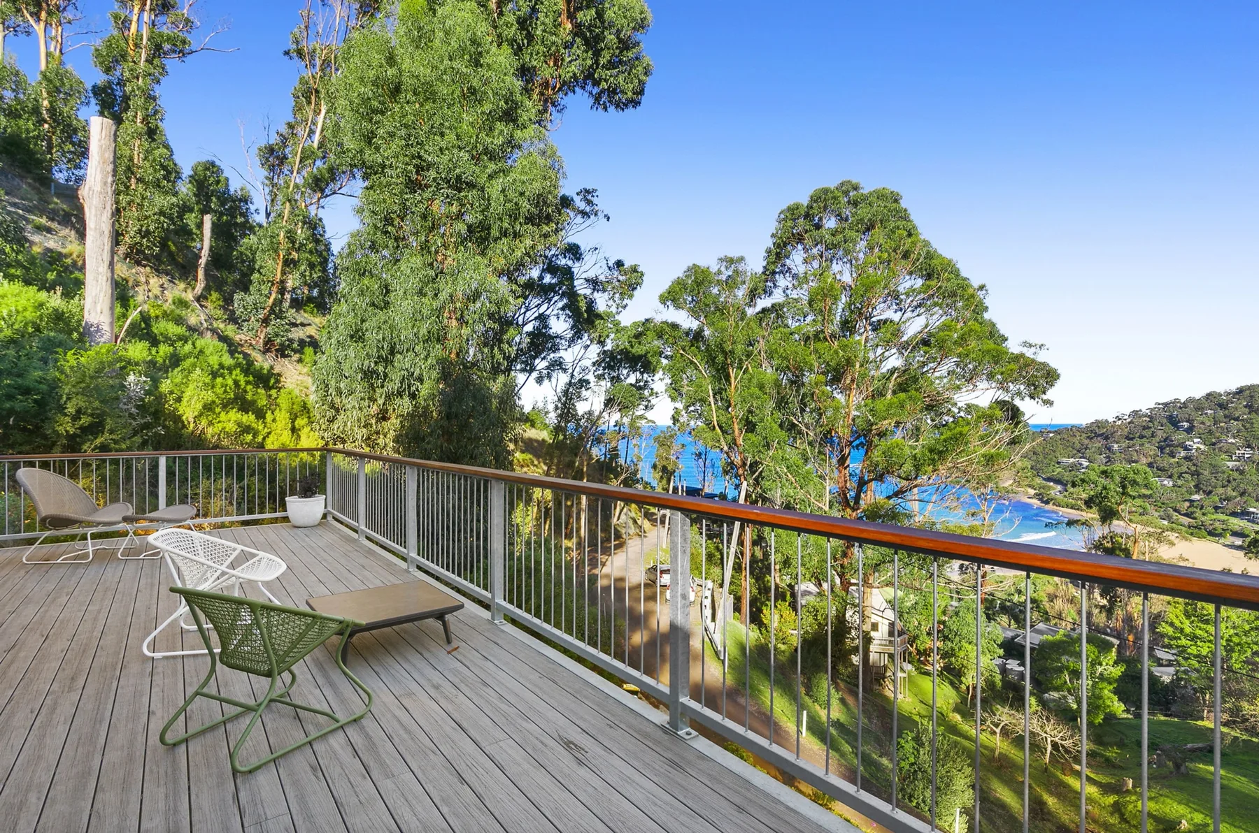 Una terraza exterior con asientos ofrece vistas de árboles y aguas azules.