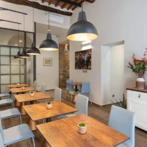 Representative hotel space: A dining area with wooden tables and hanging pendant lights.