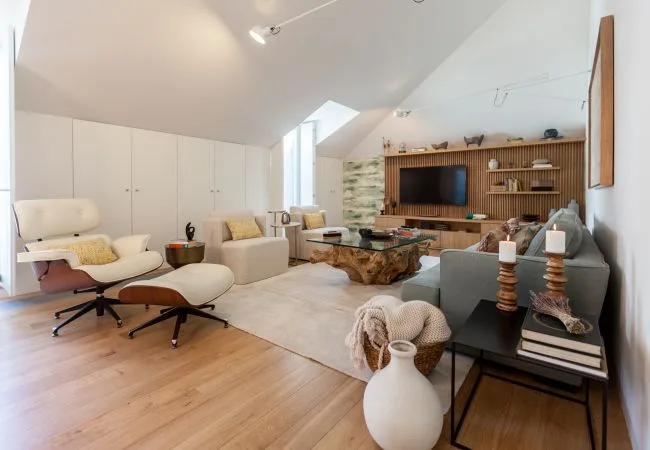 A bright living room with seating arranged around a glass coffee table and television.
