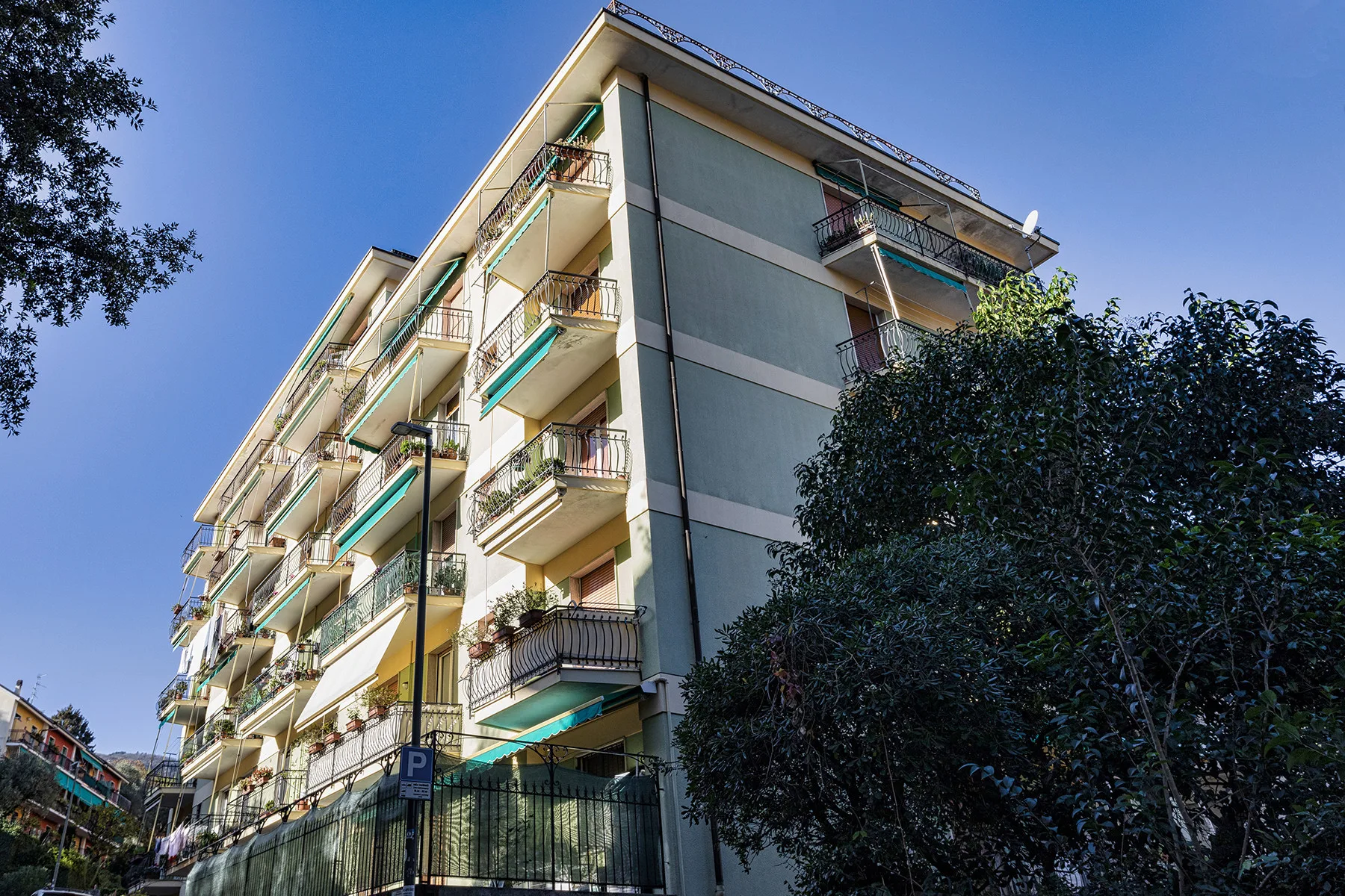 Zona común: Exterior de un edificio de apartamentos con balcones y árboles.