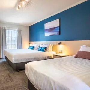 Espacio representativo del hotel: Dormitorio de hotel con camas, mesas de noche y decoración azul en la pared.