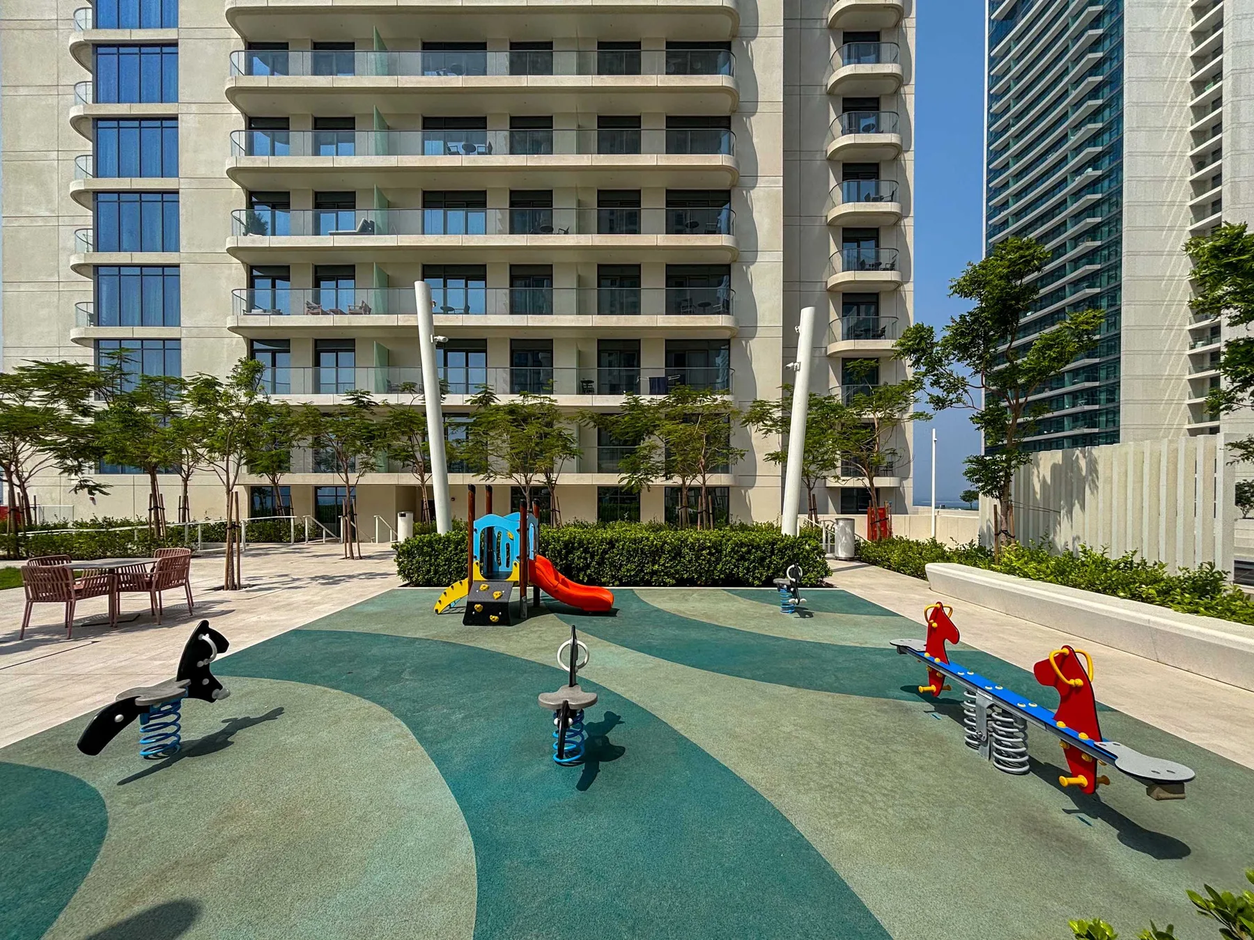 Shared amenity: An outdoor playground with colorful spring riders and a slide.