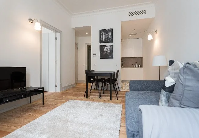 A bright living room with a dining table, seating, and a television.
