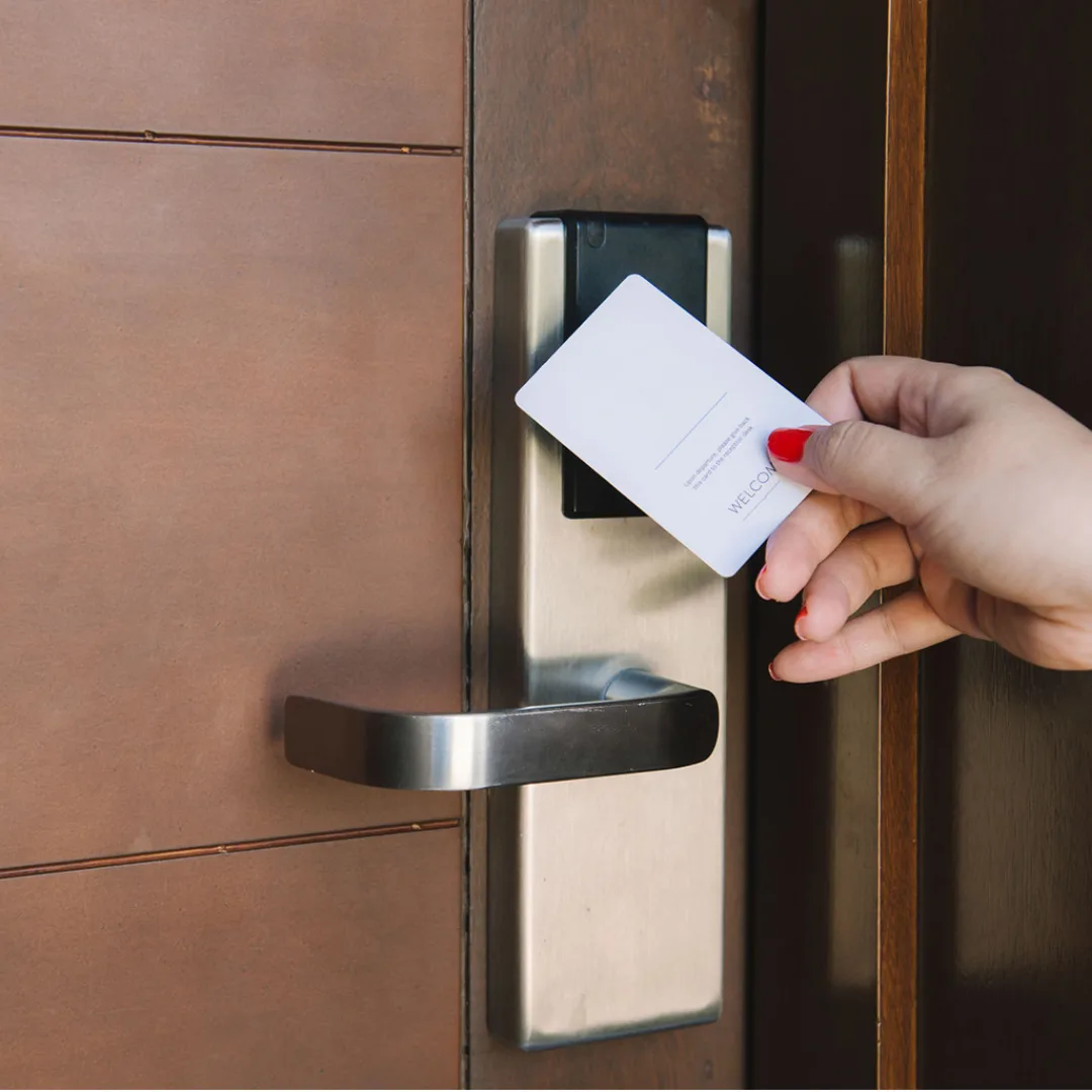 Representative hotel space: A hand holds a key card beside a hotel room door lock.
