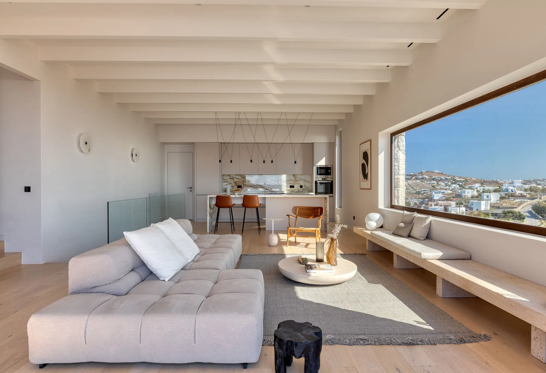 Bright open-plan living room with a large window and kitchen area.