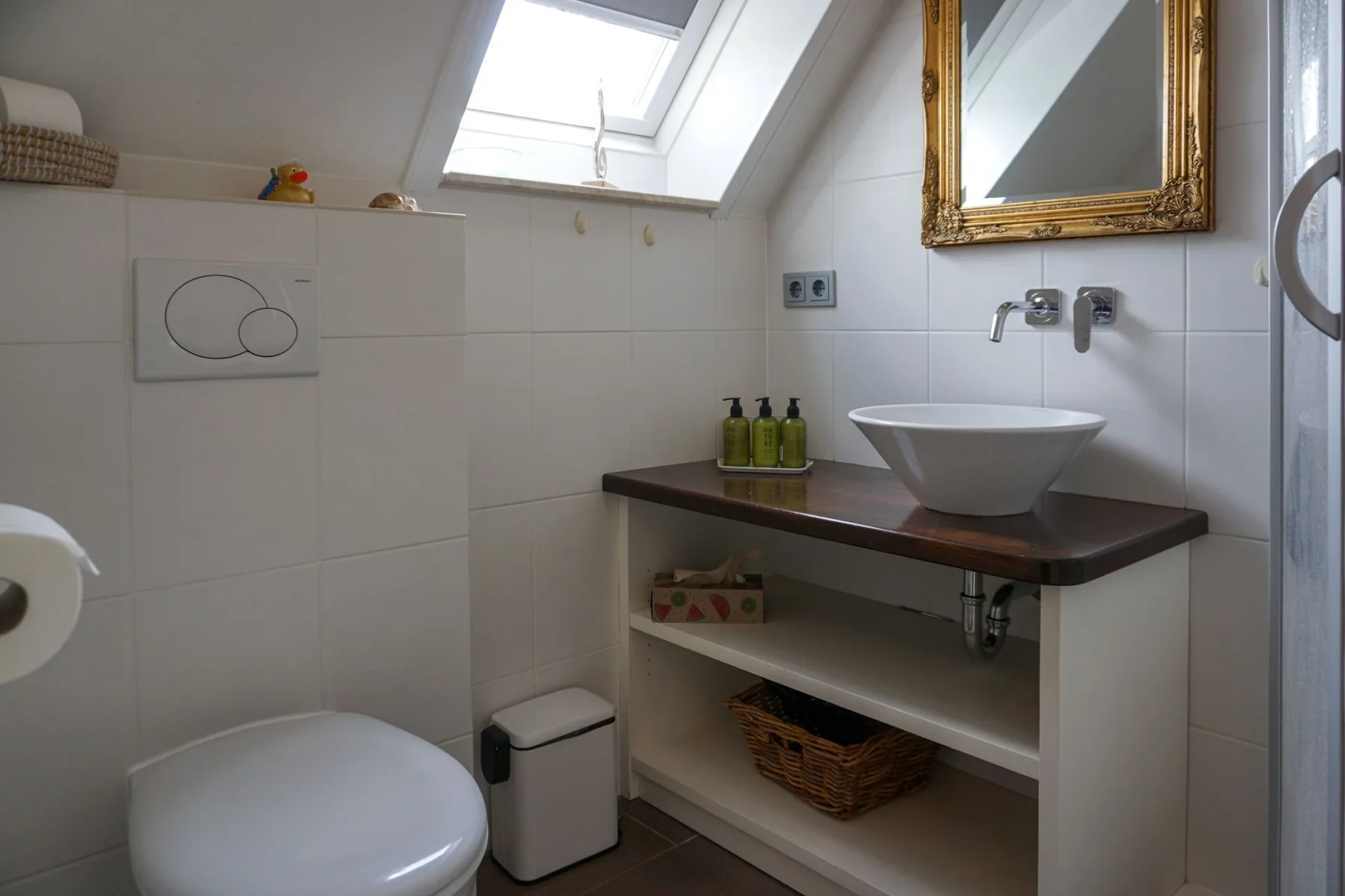 A tiled bathroom with a sink, wall mirror, and skylight.