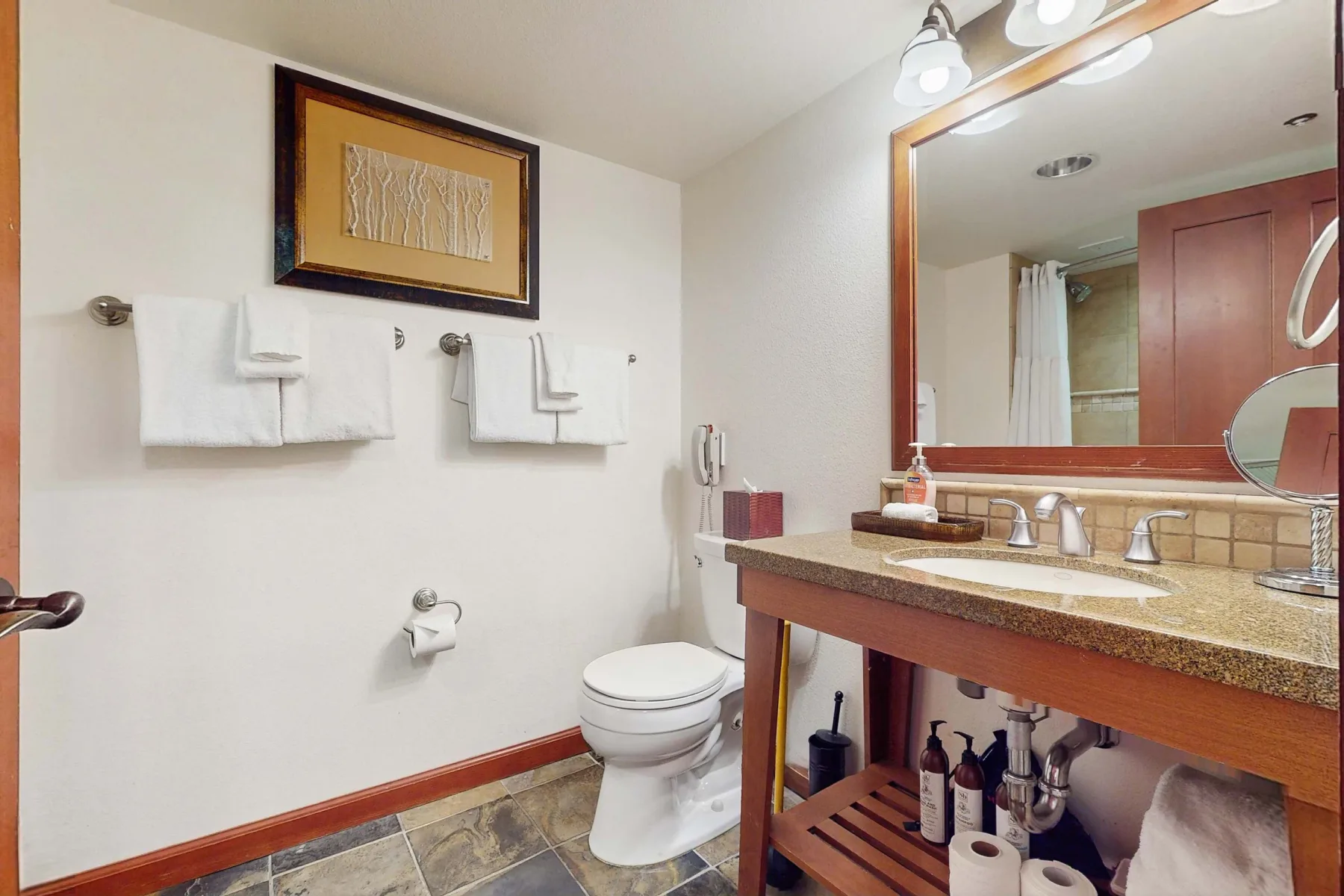 A bathroom with a toilet, towel bars, and a large vanity mirror.
