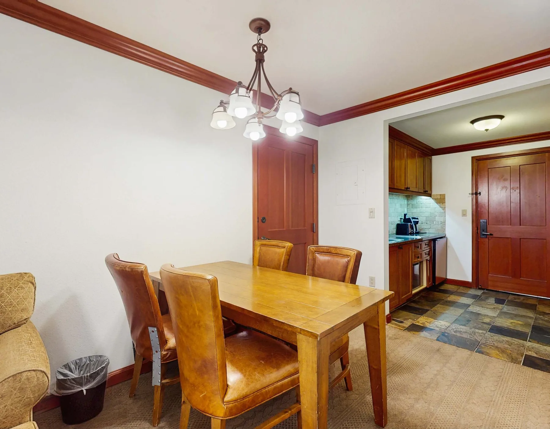 A dining area with a wooden table and seating beside an open kitchen.