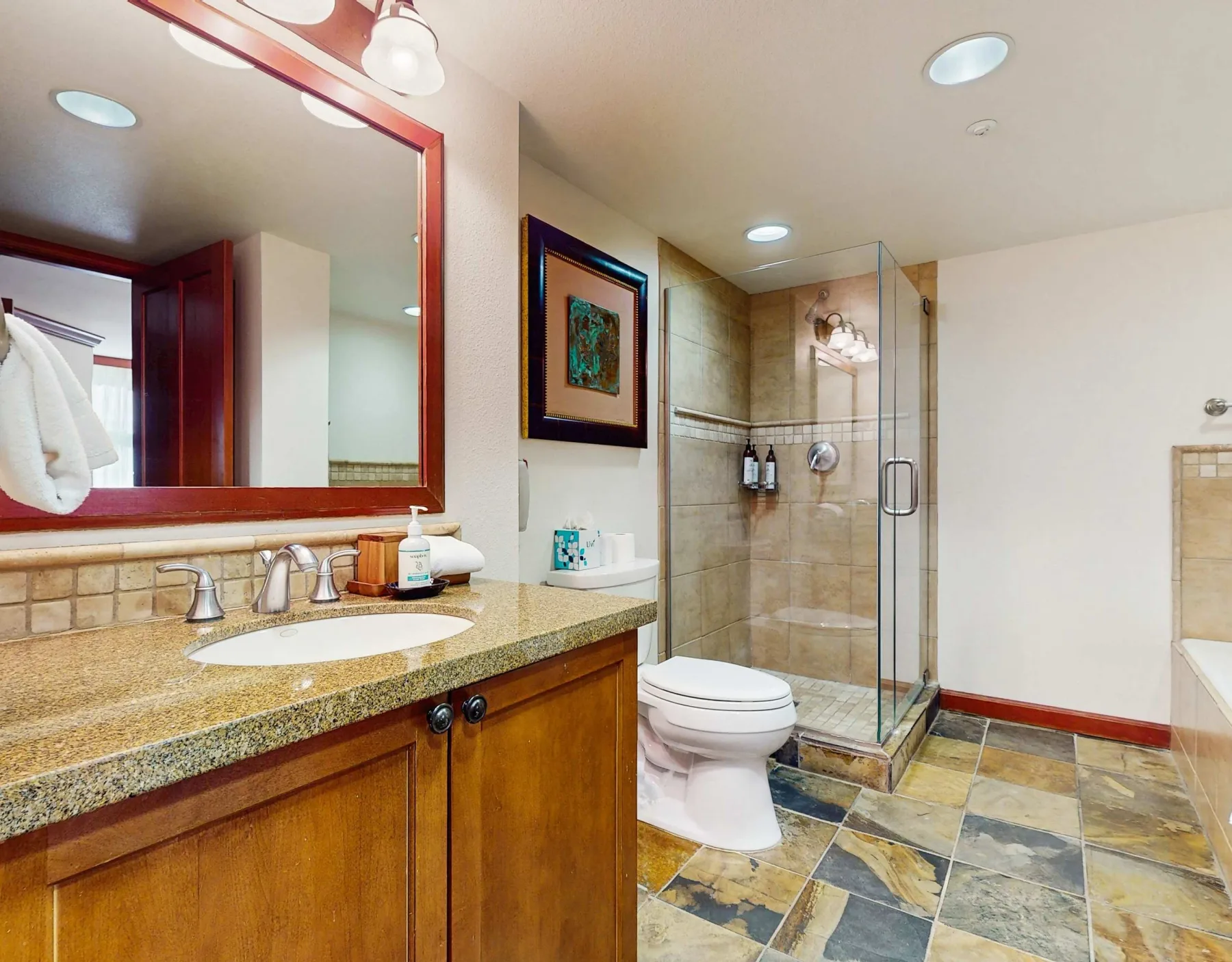 A bathroom with a vanity, sink, and glass-enclosed shower.