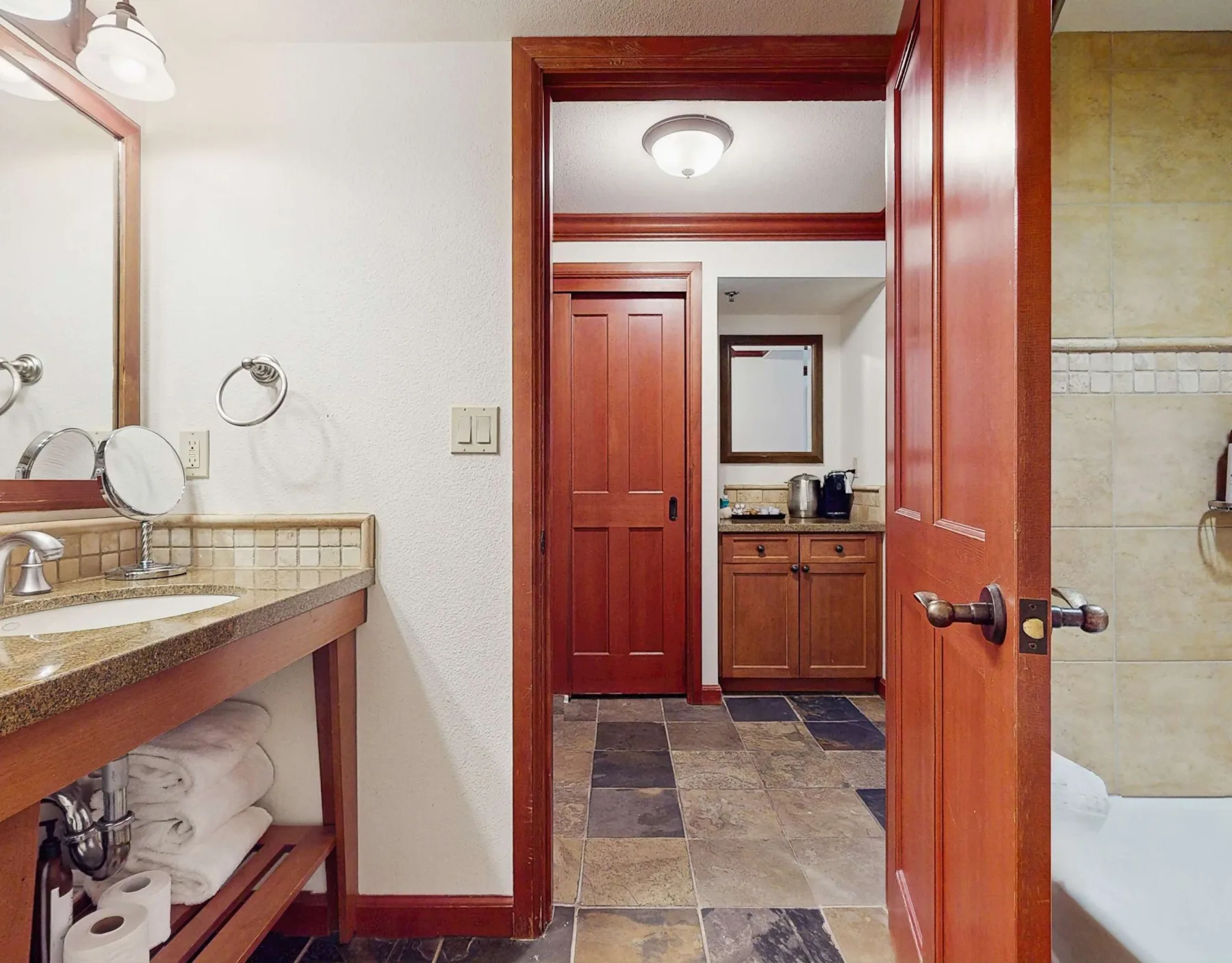 A bathroom vanity opens onto a tiled wash area with reddish wood trim.