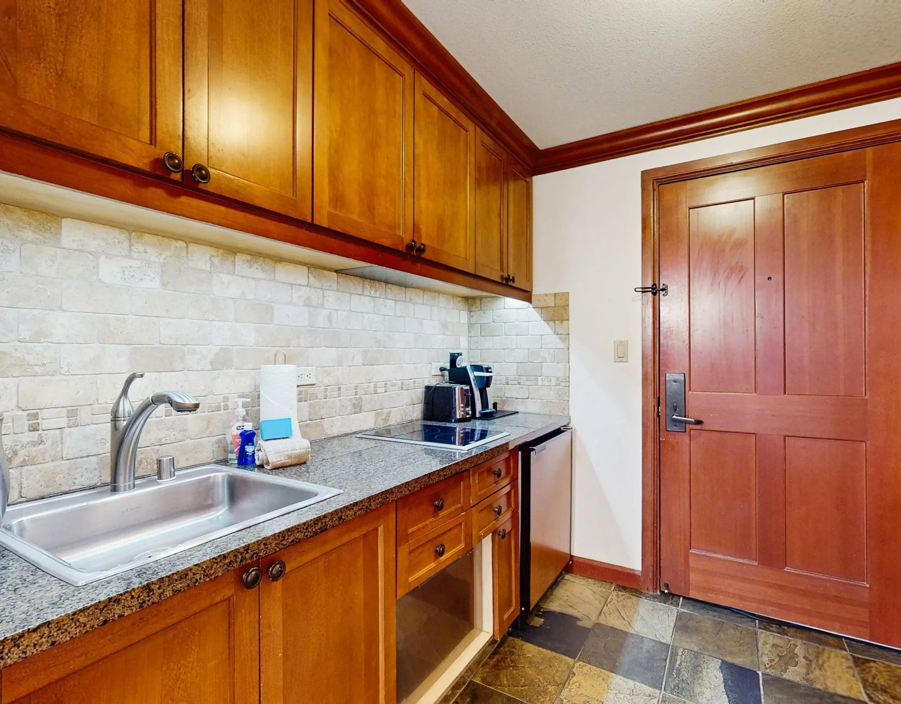 A compact kitchen with wooden cabinets, a countertop, and a sink.