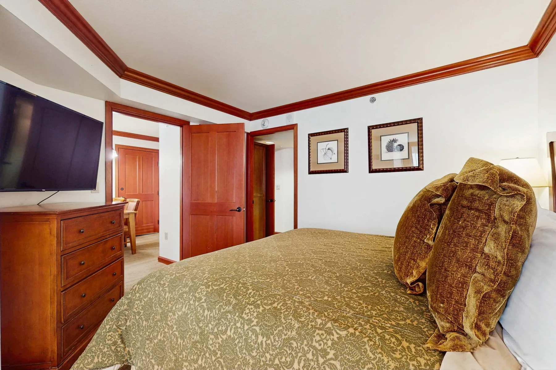 A bedroom with a patterned bedspread, a television, and an open doorway.