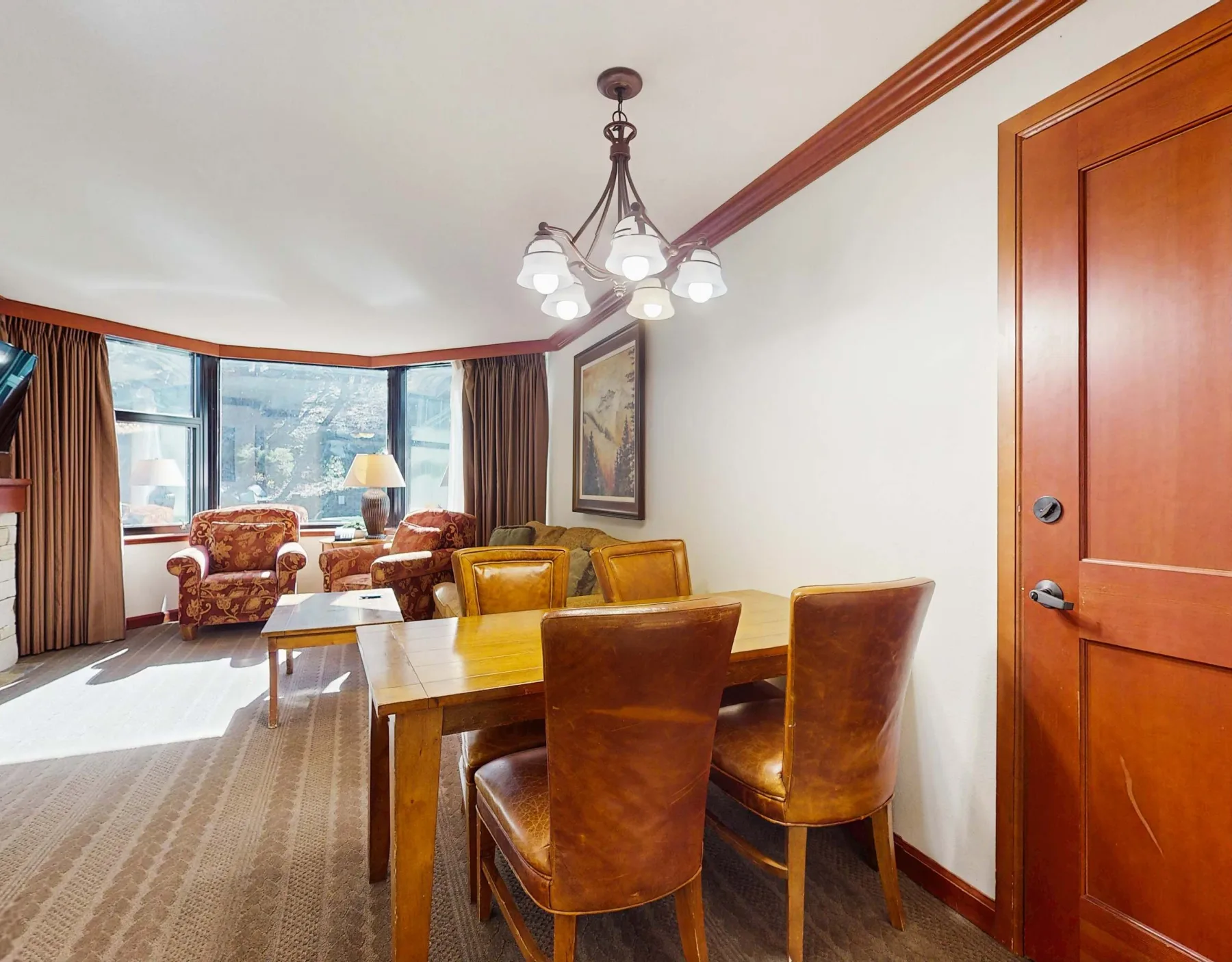A dining area with a wooden table and seating beside large windows.