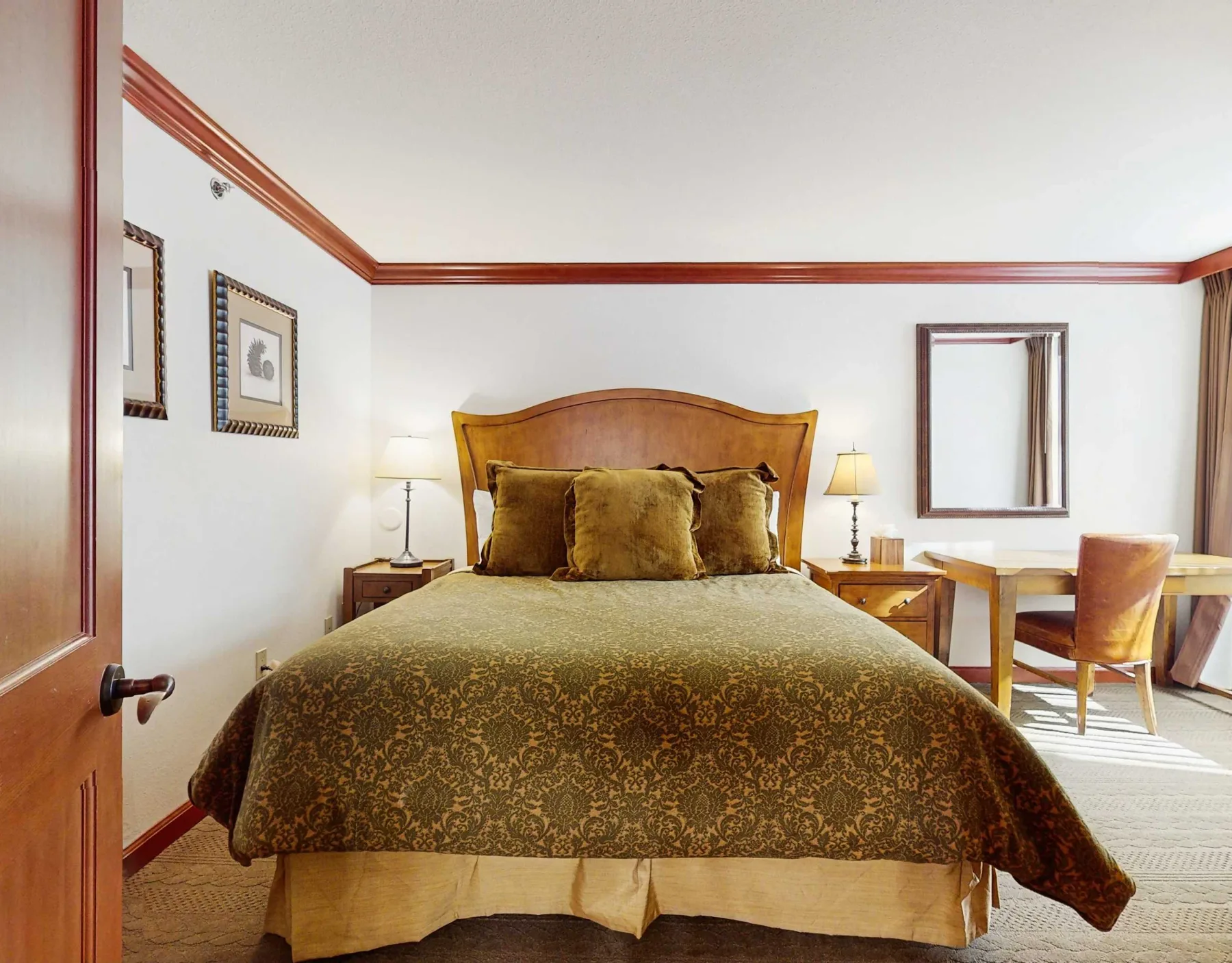 A bedroom with a large bed, bedside lamps, and a small table by the window.