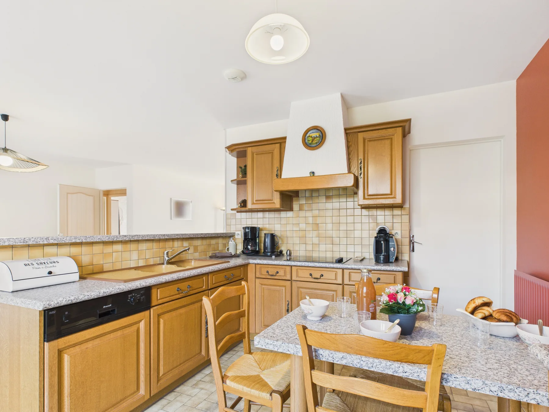 A bright kitchen with wooden cabinets and a dining table set with flowers.