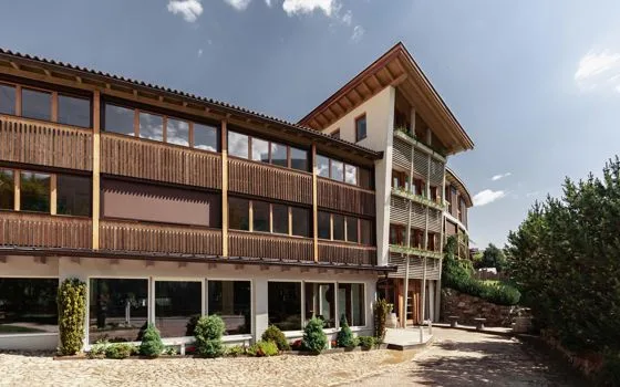 Espacio representativo del hotel: Un edificio de varias plantas con largos balcones de madera se encuentra junto a una zona pavimentada al aire libre.