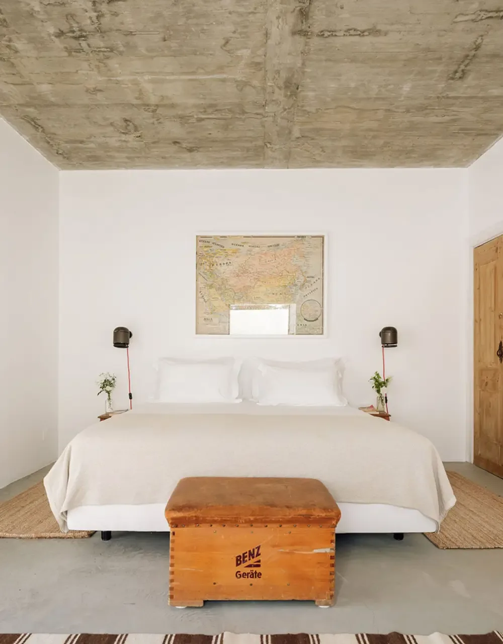 Representative hotel space: A bedroom with a neatly made bed and a map above the headboard.
