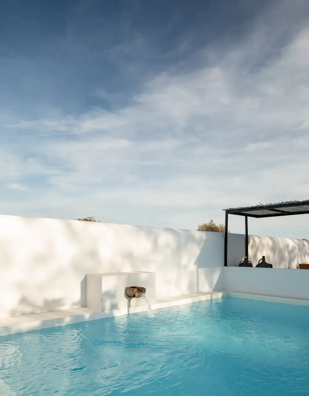 Representative hotel space: An outdoor pool sits beside a white wall beneath an open canopy.