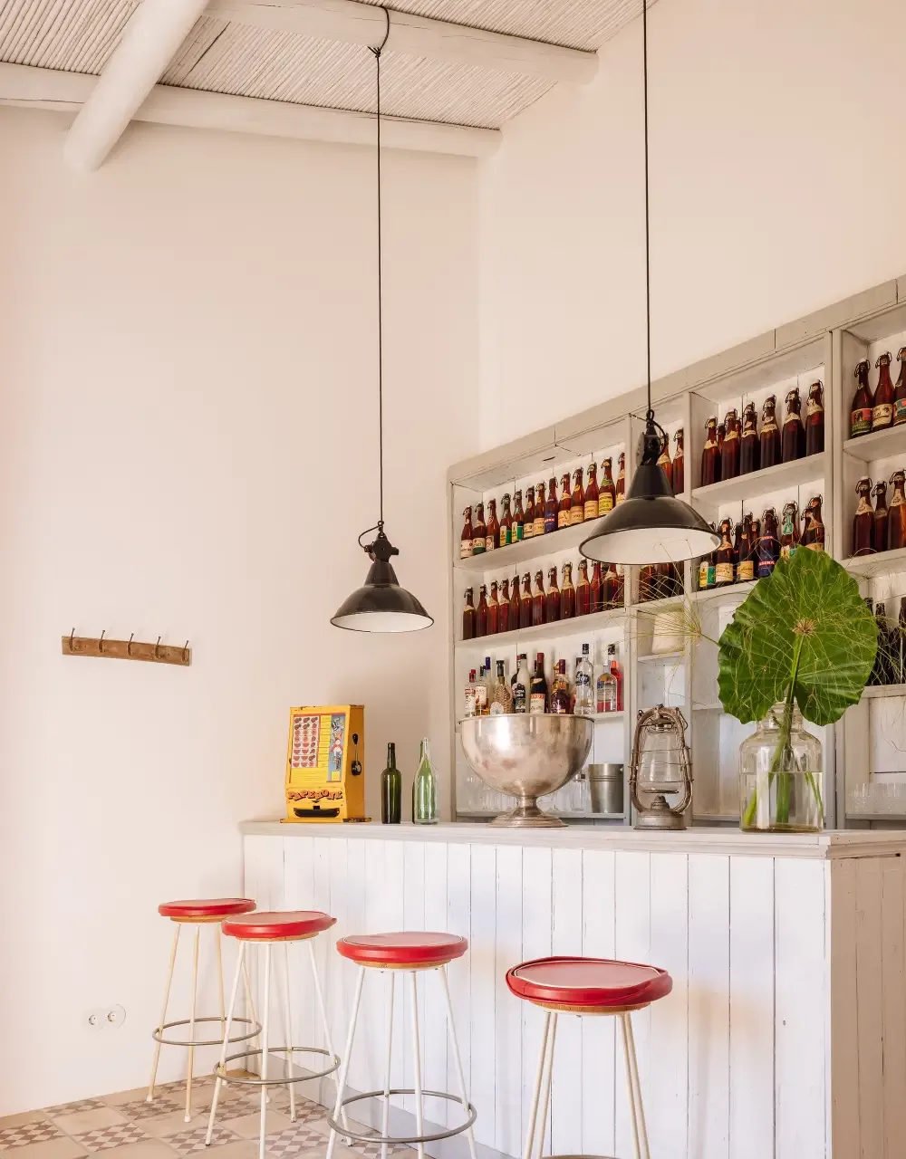 Representative hotel space: A bar counter with red stools sits beneath shelves of bottles.