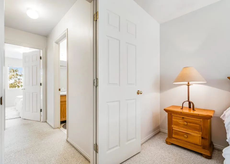 A bedroom with a wooden dresser beside an open white door.