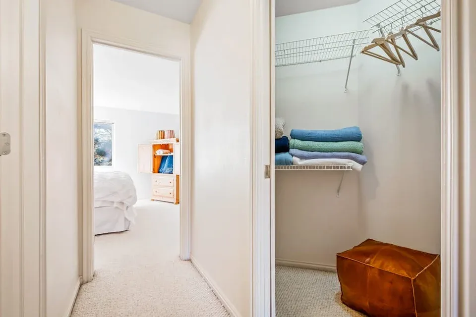 A hallway opens onto a bedroom and a closet with folded towels.