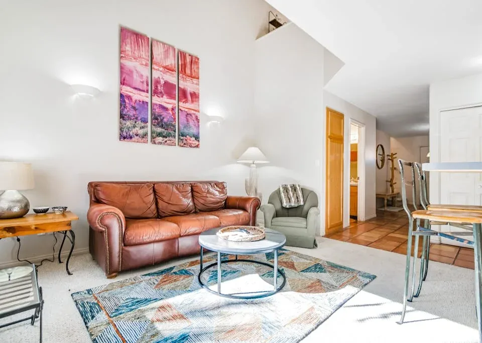 A living room with leather seating, a round coffee table, and a colorful rug.