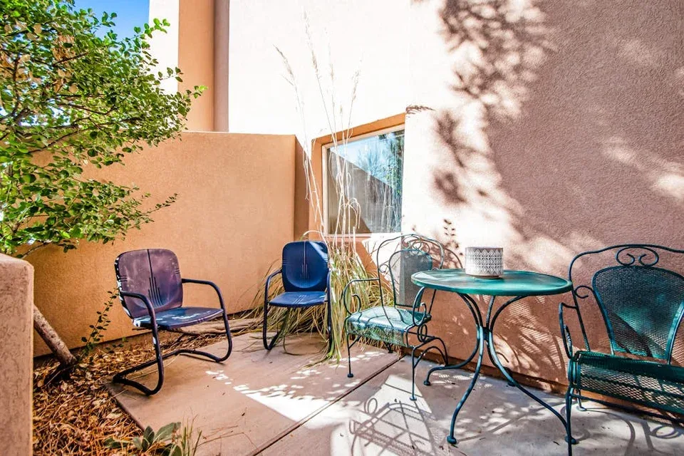 A small patio with outdoor seating and a round table beside a wall.