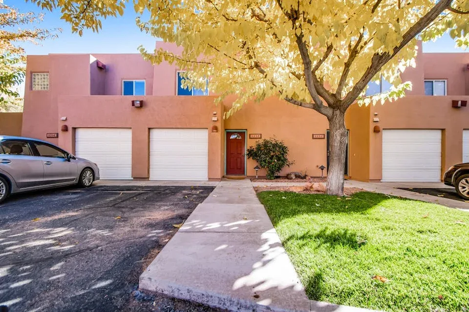 Shared amenity: A pink residential building stands behind a walkway, with a tree and lawn in front.